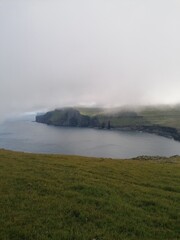 Mountain Hiking in the lush a green hills of the misty Faroe Islands