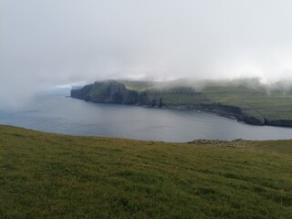 Mountain Hiking in the lush a green hills of the misty Faroe Islands