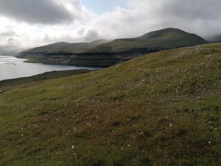 Fototapeta na wymiar Mountain Hiking in the lush a green hills of the misty Faroe Islands