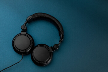 Black studio headphones with blue background and space for text