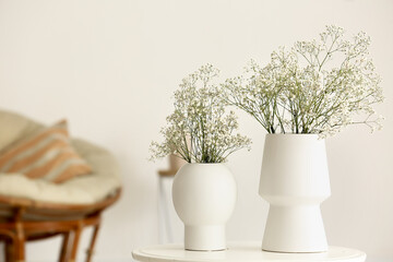 White vases with gypsophila flowers on table in living room