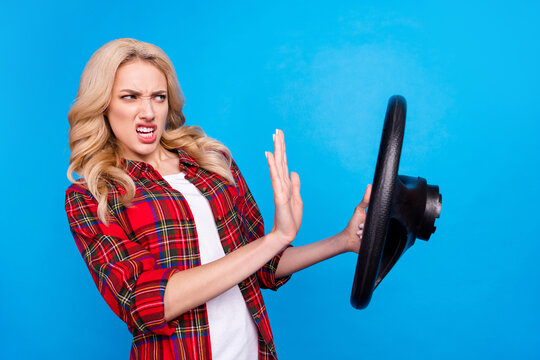 Photo of impressed angry young woman dressed checkered shirt driving vehicle beeping isolated blue color background
