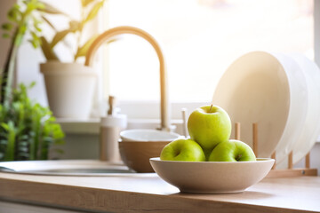 Bowl with green apples on table in kitchen, closeup