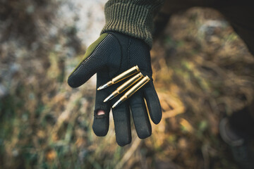 Professional hunter holding a ammunition. Hand with green gloves holding ammunition to the hunting...