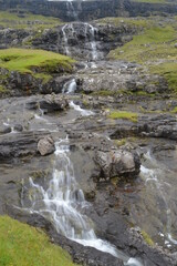 The white streaming waterfalls over the black lava rocks on the Faroe Islands in the Atlantic