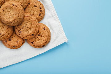 A bunch of oatmeal cookies with chocolate on a napkin on a blue background