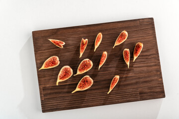Ripe fresh figs sliced on wooden kitchen board on white background. Top view.