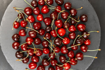 Obraz na płótnie Canvas Top view gray plate with ripe sweet red cherry. Seasonal berries. Homemade organic cherries.