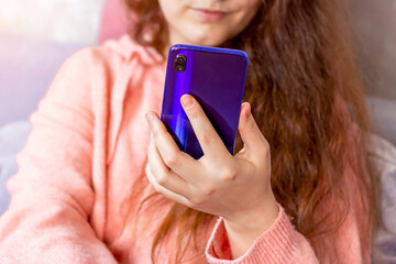 White Caucasian brunette woman holding in her hand and using mobile phone app at home.