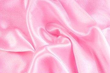 Obraz premium Light pastel pink color silk wavy textile pattern as a smooth textured background. Rose colored soft satin fabric drapery.