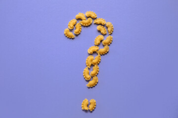 Question mark made of dry pasta on purple background