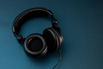 Black studio headphones with blue background and space for text