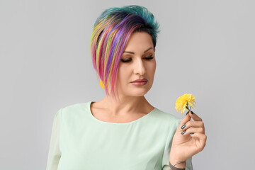 Beautiful woman with unusual hair and flower on grey background