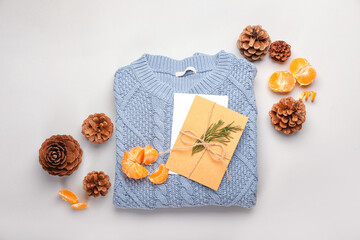 Beautiful winter composition with sweater, card, tangerines and cones on white background