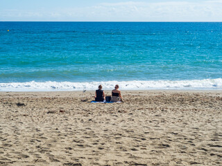 Dos chicas jóvenes sentadas en la orilla de la playa de Fuengirola