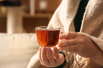 Woman drinking tasty tea at home, closeup