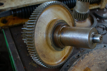 An old rusty gear lies on a table in a garage for repairs.