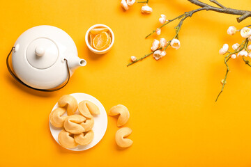 Tasty fortune cookies with tangerines and Chinese tea on color background