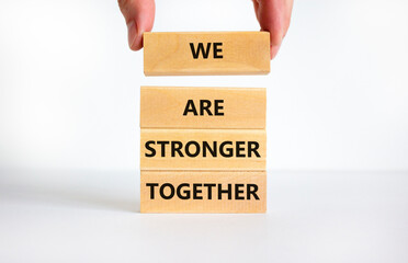 We are stronger together symbol. Concept words We are stronger together on wooden blocks. Businessman hand. Beautiful white background, copy space. Business and we are stronger together concept.
