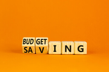 Budgeting and saving symbol. Wooden cubes, changed the word saving to budgeting. Beautiful orange background, copy space. Business, budgeting and saving concept.