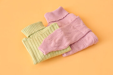 Folded roll-neck sweaters on color background