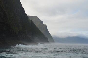Fototapeta na wymiar The dramatic coastline of the Faroe Islands with green mountains in the background