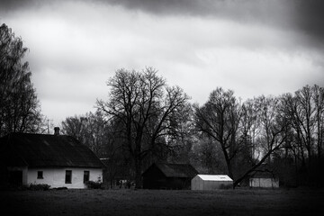 countryside house with barn and greenhouse in autumn, black and white gloomy look