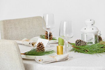 Beautiful table setting with pine cones and fir branches indoors
