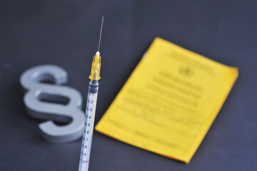 Hamburg, Germany - December 22, 2021: Close up of a hypodermic syringe, a paragraph sign and...