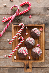 Board with tasty candy cane cookies on wooden background