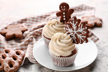 Tasty Christmas cupcakes with gingerbread cookies on light background