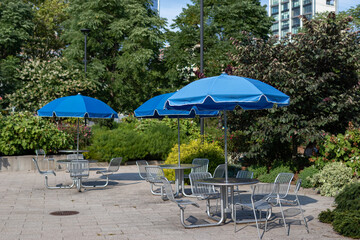 Empty Tables and Chairs with Umbrellas at Hudson River Park in New York City during the Summer