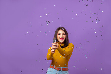 Young Asian woman in yellow long-sleeved shirt and cheerful with shooting confetti on isolated...