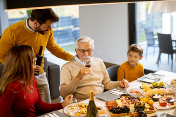 Young man poring red wine to his father for testing during at home