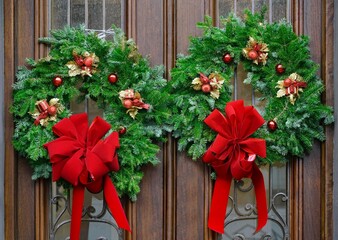 Fototapeta premium Wood grain double front door with wreath made of pine branch with red ribbons