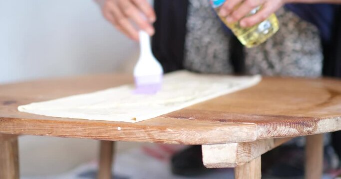 Female Hands Of Baker Rolls Dough In Flour On Wooden Board On Table With A Rolling Pin, In Bakery Shop, Woman Making Pizza Using Traditional Recipe At Home.