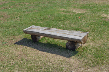 Bench made of longitudinally sawn wood on green grass
