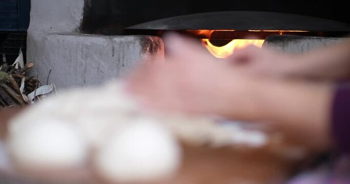 Baker hands kneading dough in flour on the table

