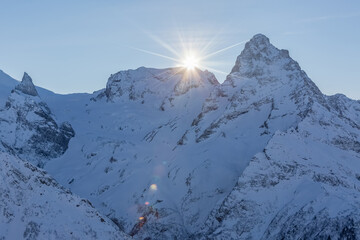 The sun sets behind the snowy mountains. Natural scenery. Travel and hiking.