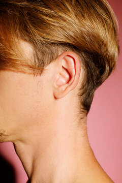Close up picture of man ear over pink background. Ear health concept