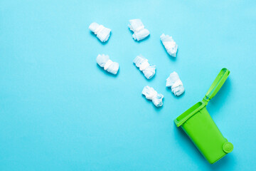 Naklejka premium Throw away folded medical masks in a green container for recycling on a blue background. Blue face masks after use. Using medical masks