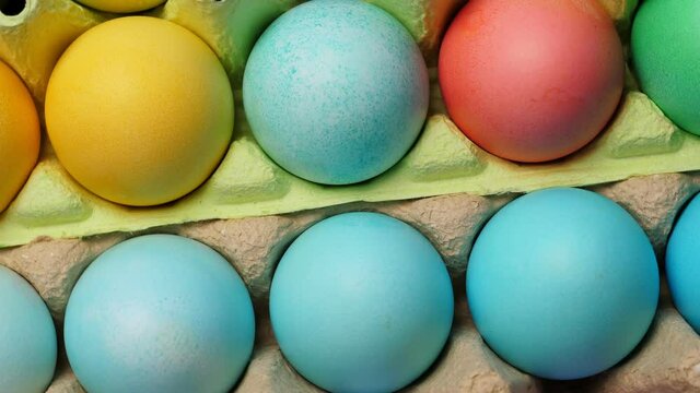 Painted easter eggs in pack. Closeup on black slate background. Rotating