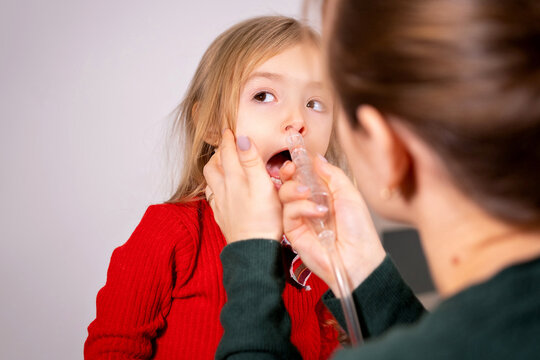 Mother Rinse Her Little Girl Nose With Inhalation Apparatus To Clean The Nose, The Girl Is Calm And Doing The Procedure.