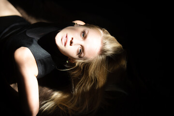 Portrait of young attractive woman. Dramatic and sensual portrait of a beautiful girl isolated on a dark background in studio. Blonde woman closeup face.