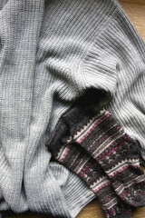 Gray sweater, warm gloves and socks on wooden background. Top view.