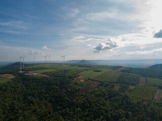 Aerial View of a wind turbine on top of mountains, blue sky as background. - Sustainable development, environment friendly, renewable energy concept.