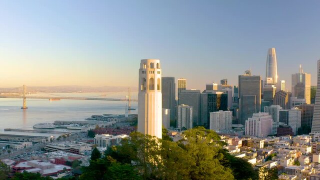 4K aerial video footage partially rotating around a tower in San Francisco, California at sunset. Golden light on tower, Bay Bridge in the background.	

