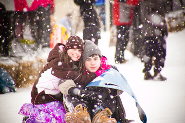 Siblings posing for a picture during a snowfall