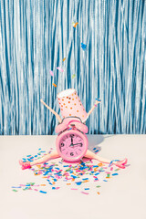 Funny creative idea of a pink watch, woman and confetti. The atmosphere of New Year's and Christmas...