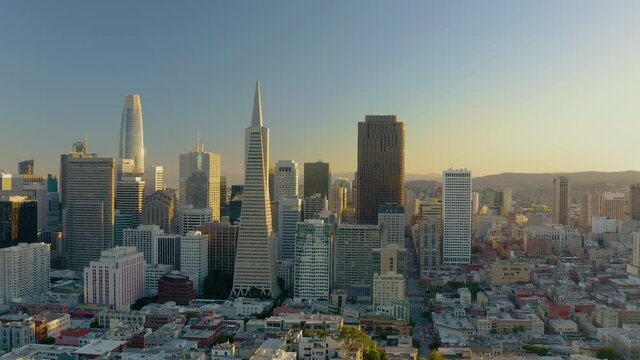 4K aerial daytime video footage of San Francisco, California, at sunset, as seen coming from Pier 39 area towards Coit Tower which is passed on left of frame.
